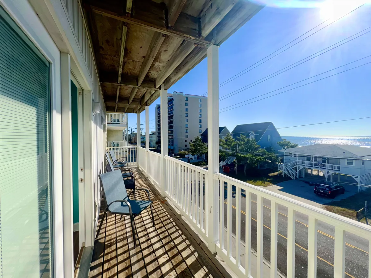 An inviting exterior view featuring a balcony with outdoor chairs set against the backdrop of the ocean. The tranquil mood is accentuated by the open sky and the sense of relaxation, suggesting guests enjoying the sea breeze and the beautiful scenery from the comfort of their private outdoor space.