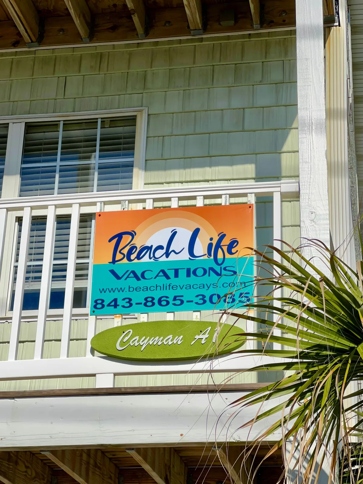 This exterior image features the welcoming 'Beach Life Vacations' and 'Cayman A' signs, accented by palm leaves, under bright natural light. The signage and tropical foliage establish a strong sense of place, inviting guests to embark on the adventures described in the section. The mood is cheerful and anticipatory, suggesting the beginning of a memorable vacation experience.