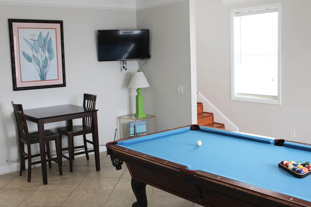 A relaxed, sociable room centers on a pool table and a small dining table, with a TV and framed artwork adding to the inviting vibe. The space feels ideal for winding down after sampling local restaurants or planning the next culinary adventure.