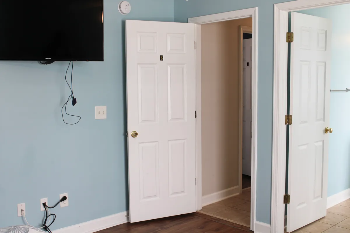 This photo presents a relaxed, inviting living area with a wall-mounted television, open doorways leading to other parts of the property, and light blue walls. The space is arranged for group gatherings and casual relaxation, suggesting comfort and versatility for unwinding after local adventures.